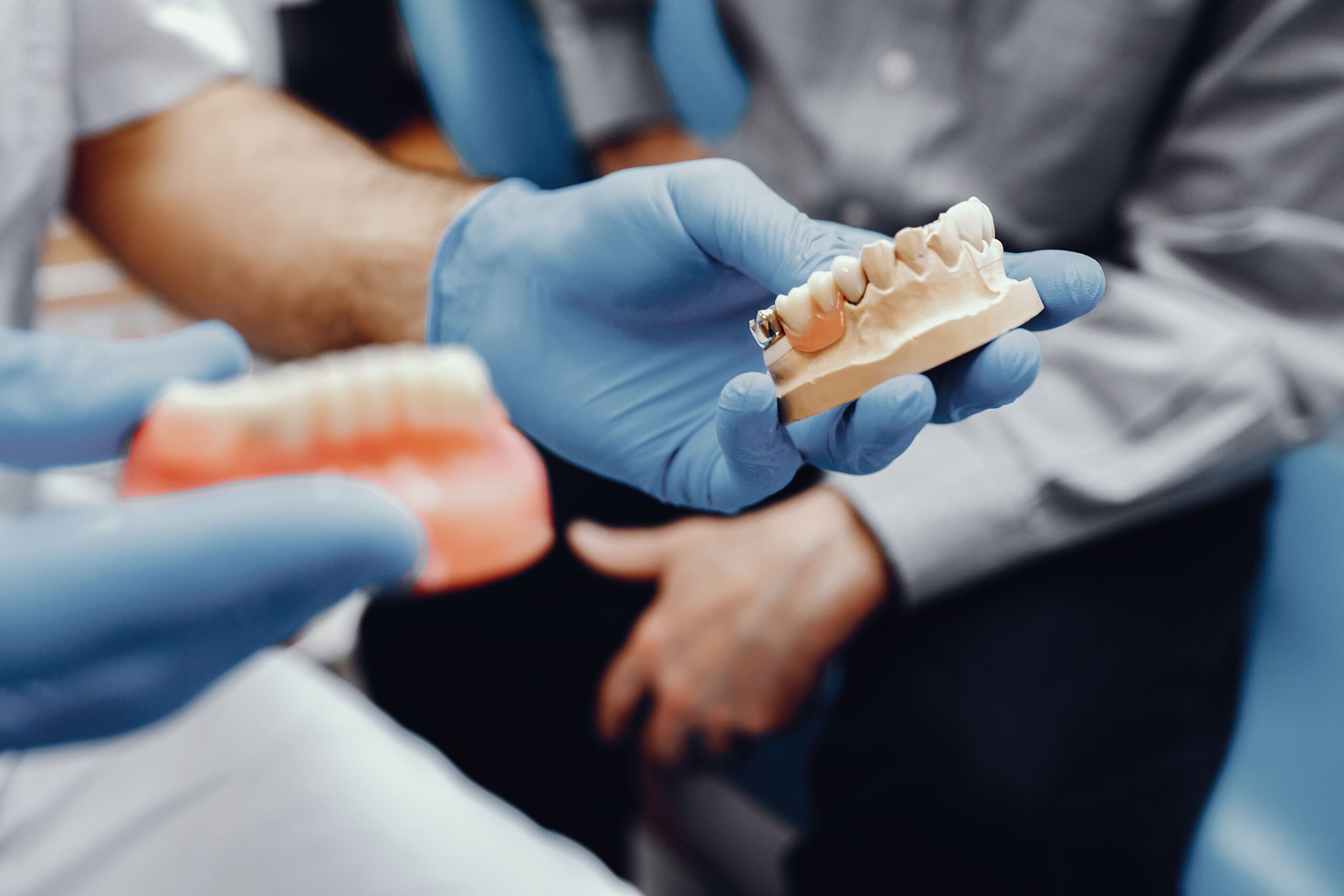 Dentista mostrando una prótesis dental y un molde de dientes en una clínica dental